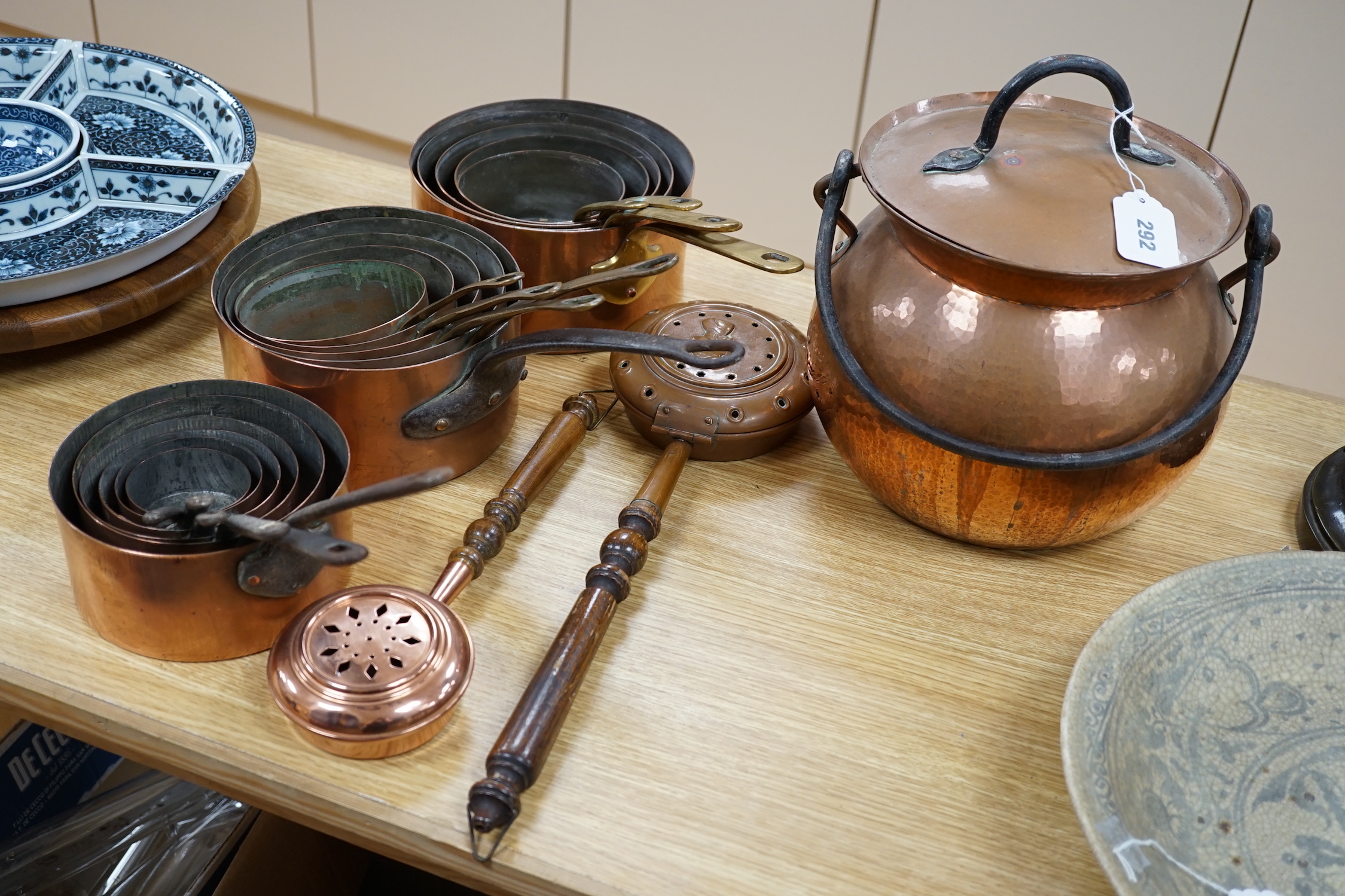 A quantity of various copper-ware including graduated pans, lidded cauldron and miniature warming pans, largest 39cm wide